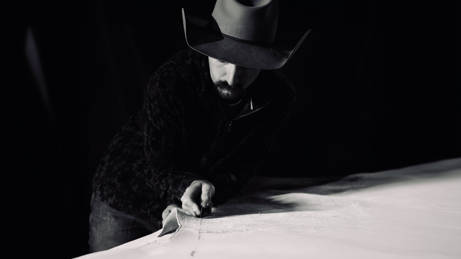 Man wearing a hat and dark clothing, sitting at a table with a map.